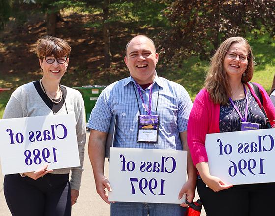 Alfred University alumni group photo holding grad year signs